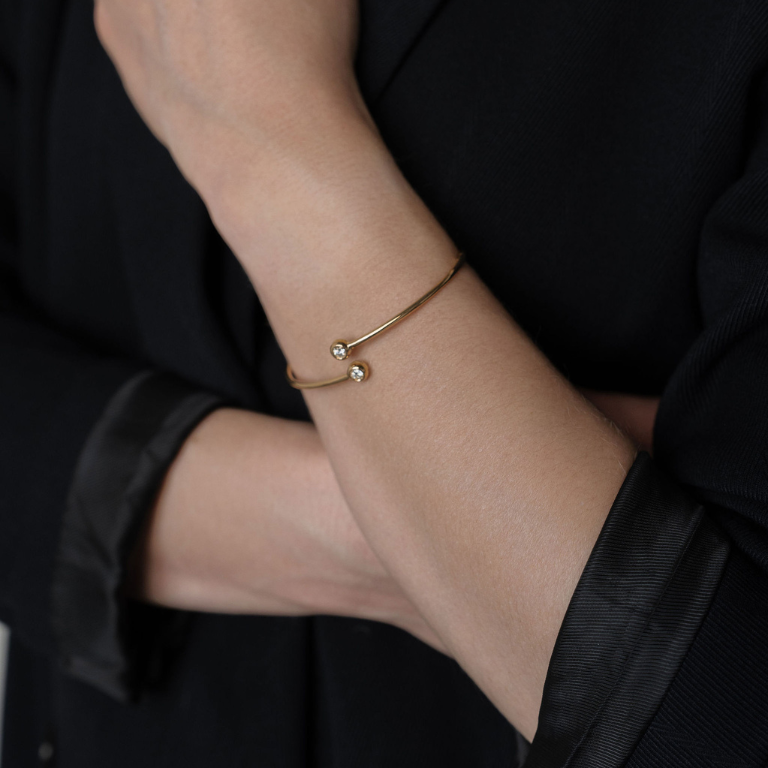 Gold bracelet on a wrist with a black background