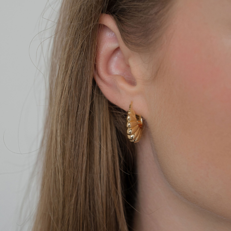 Gold hoop earrings worn by a person with light skin and blond hair.