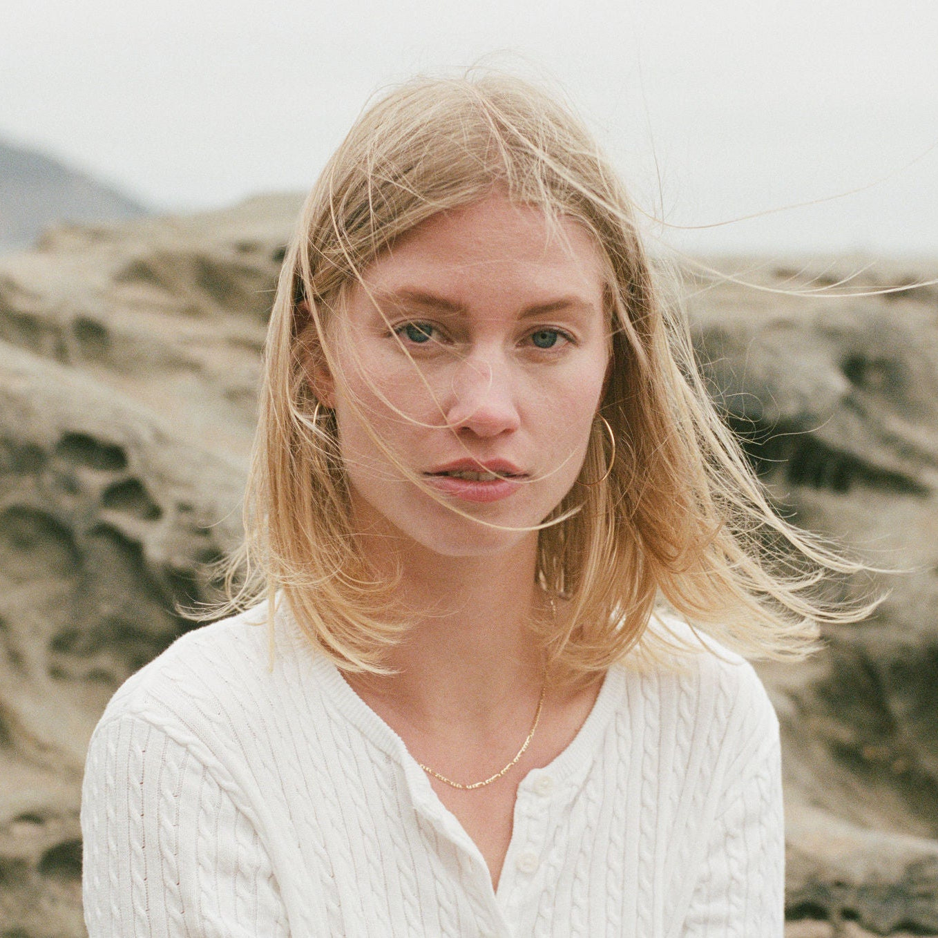 Women with blond hair with a figaro gold chain and bold earrings