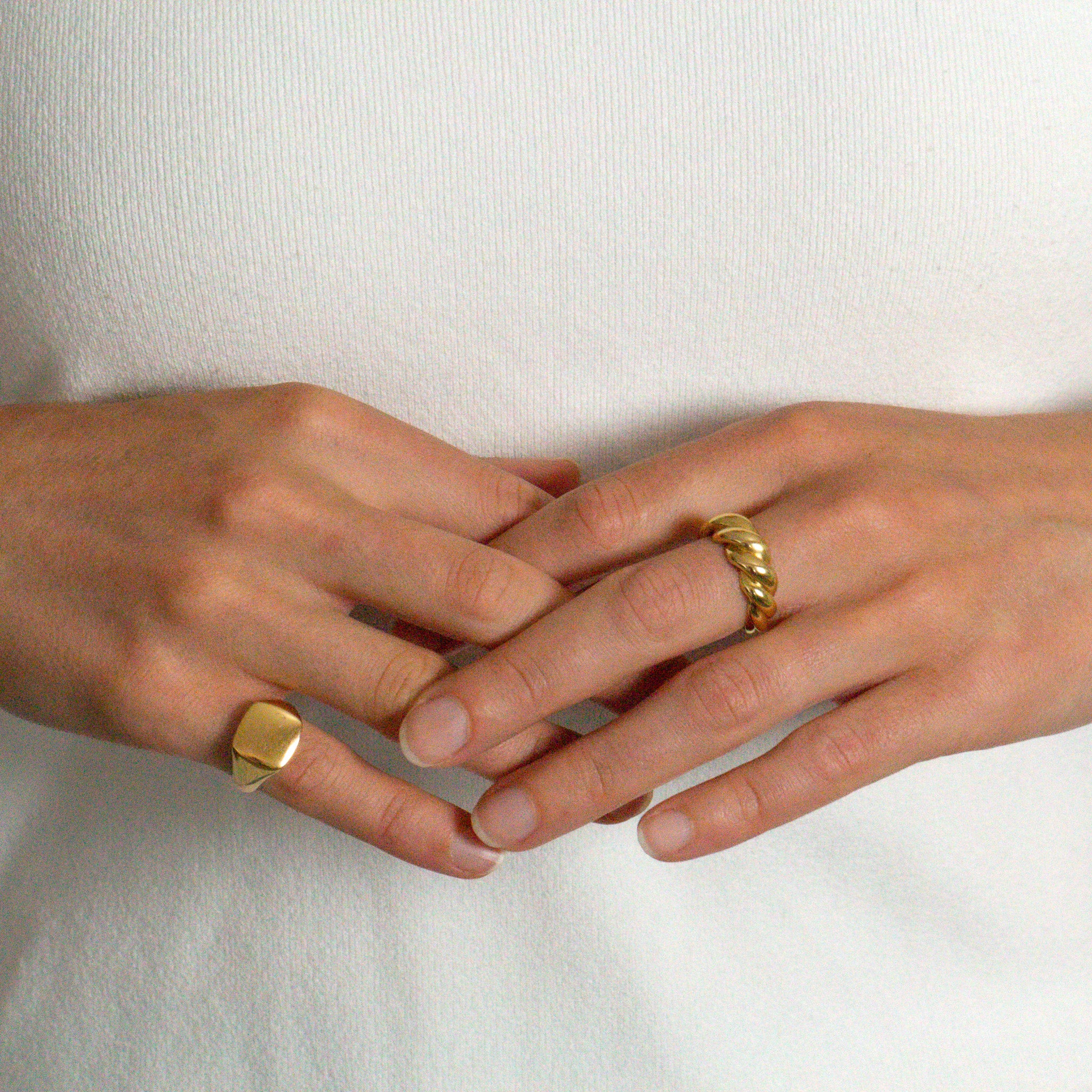 Two hands with gold rings on a white background