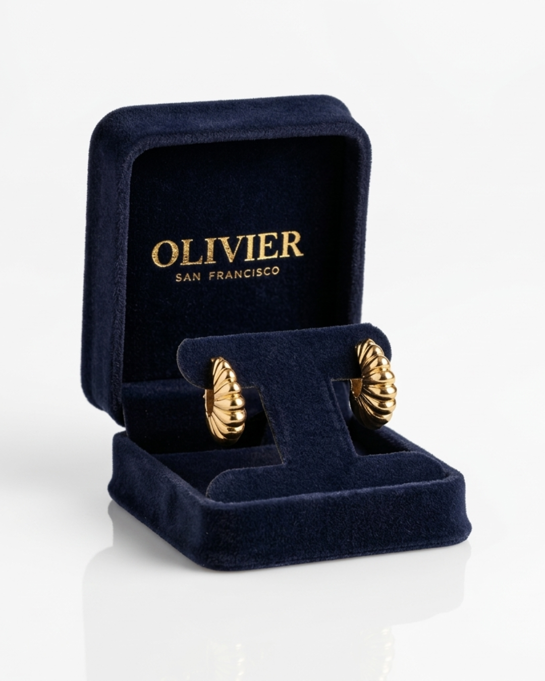 Gold earrings in a navy blue Oliver box on a white background