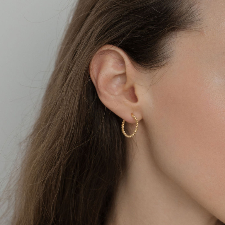 Person wearing beaded gold 15mm hoop earrings 
