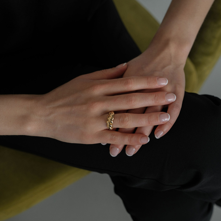 Close-up of hands with a gold ring on a neutral background