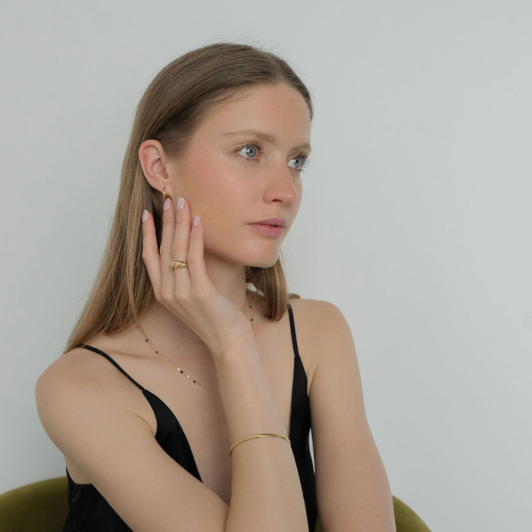 Woman wearing gold jewelry against a plain background