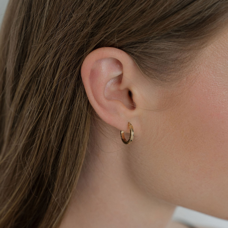Close-up of a person wearing a gold hoop earring.
