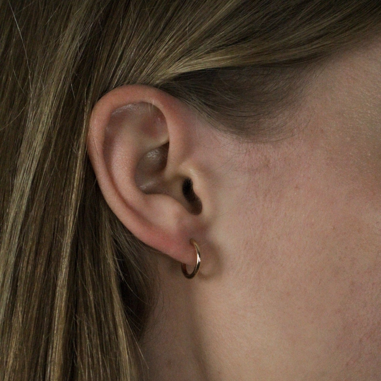 Mini gold hoops earrings on model