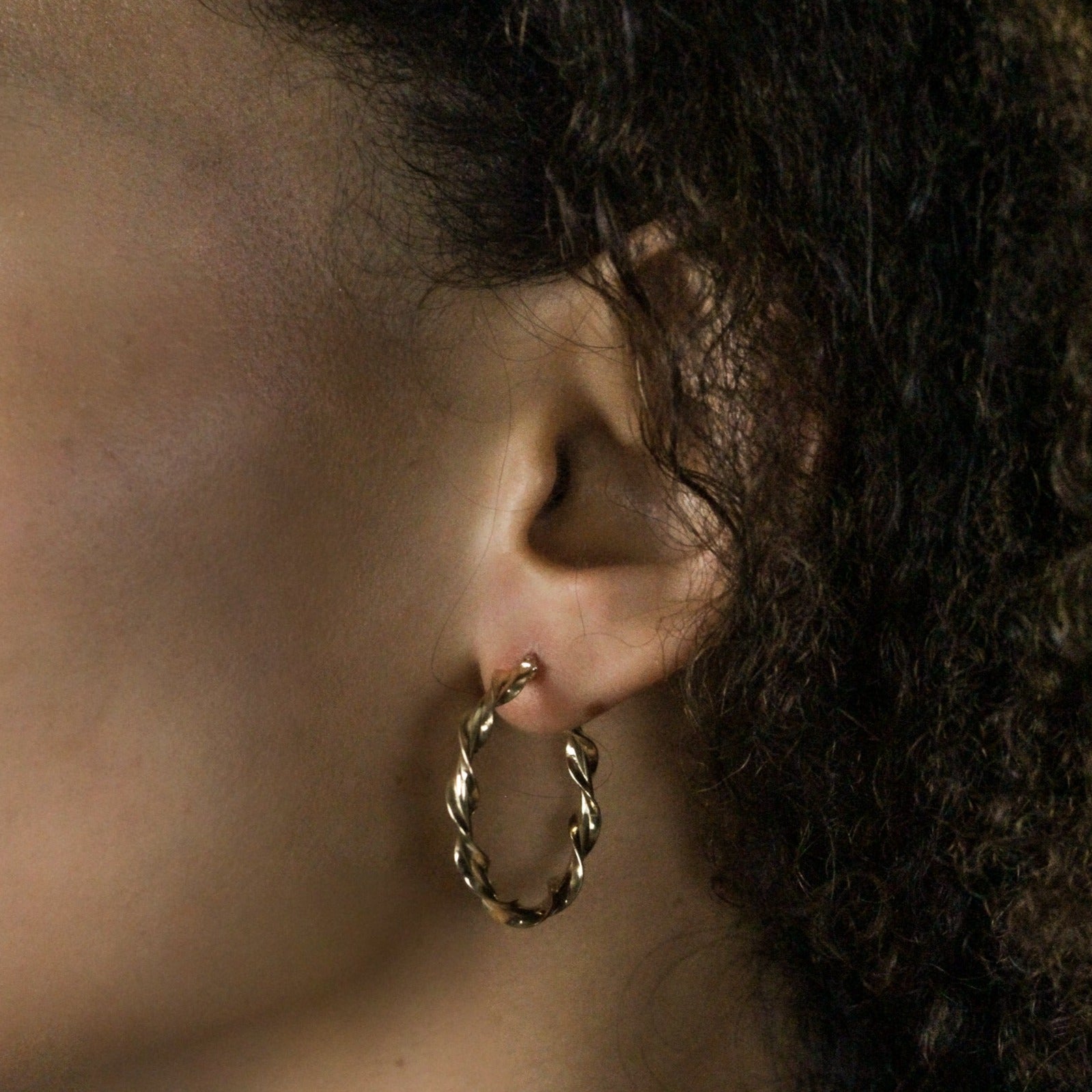 Gold hoops vine earrings on model, side angle