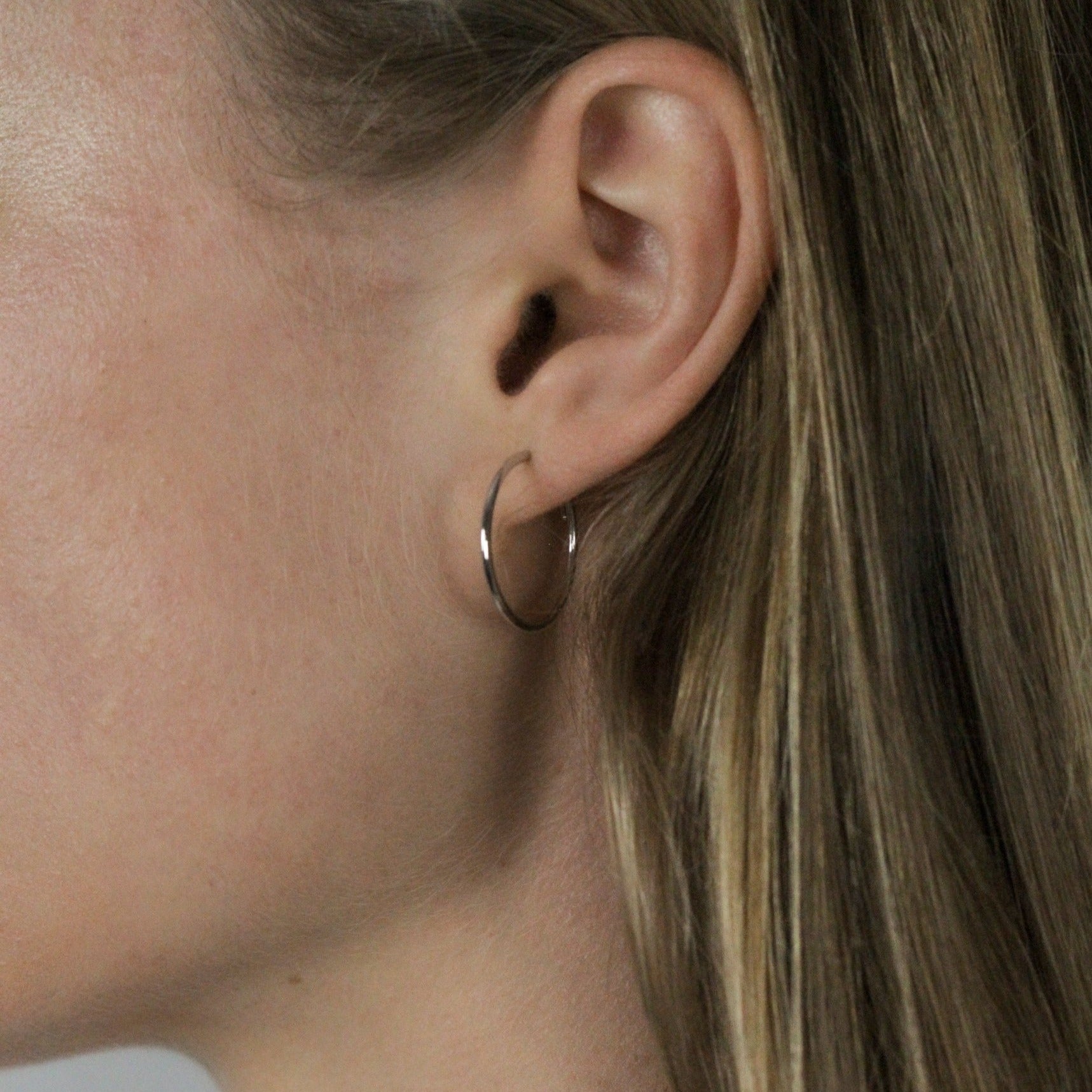small white gold hoops earrings on model, other angle